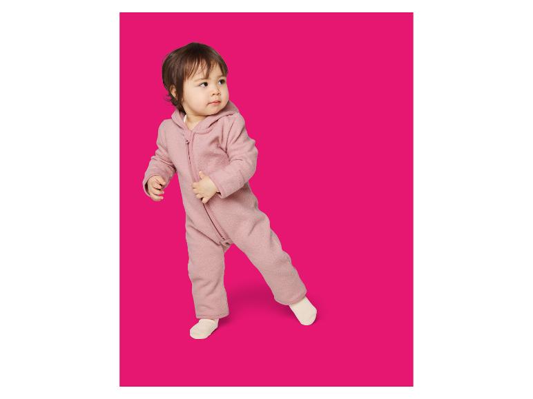Kleinkind in einem rosa Kapuzen-Fleece-Overall, schaut zur Seite.