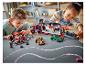 Zwei Kinder spielen mit LEGO Speed Champions Sets, darunter ein Transporter und Rennwagen.
