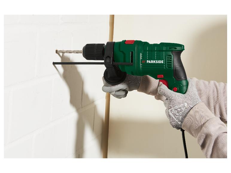 Grüne Parkside Bohrmaschine in Gebrauch, bohrt in eine weiße Wand.
