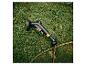 Schwarze Gießpistole mit gelben Akzenten und Gartenschlauch auf Gras.