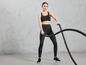 Eine Frau in Sportkleidung trainiert mit einem Battle Rope.