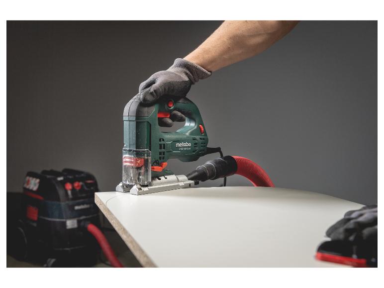 Metabo Stichsäge schneidet Holz, an Staubsauger angeschlossen, Hand mit Arbeitshandschuh.
