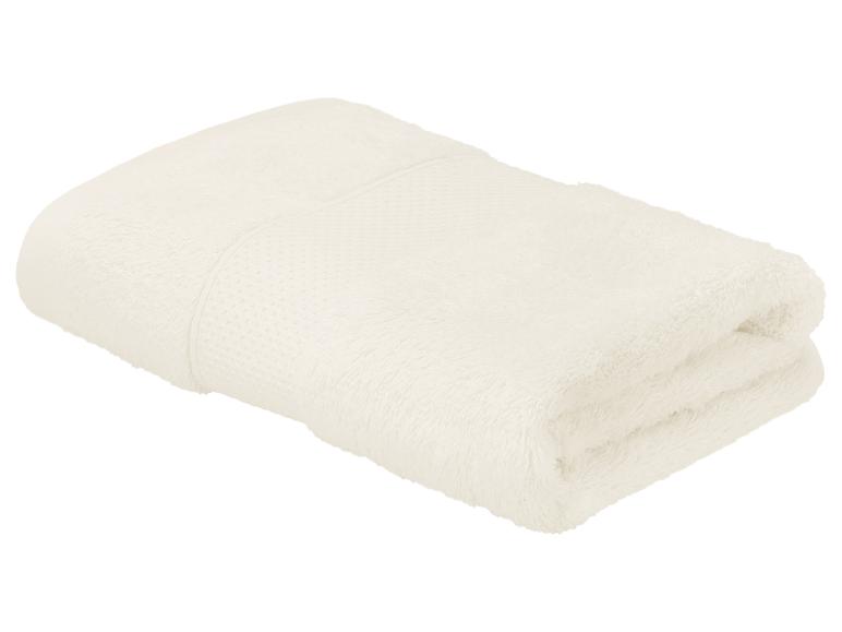 Gefaltetes cremefarbenes Handtuch mit strukturiertem Band, isoliert auf weißem Hintergrund.