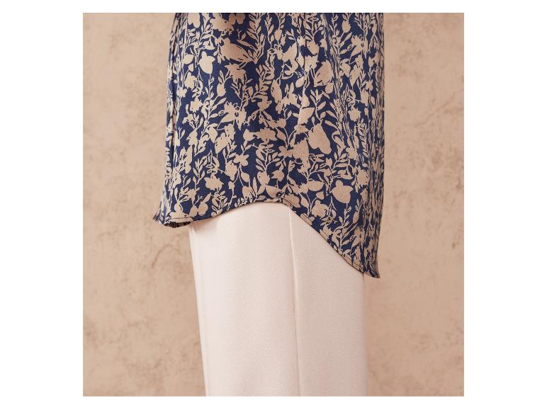 Eine dunkelblaue Bluse mit beigefarbenem Blumenmuster und eine beige Hose.