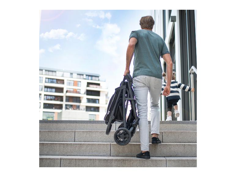 Mann mit Kinderwagen und gestreiftem Kind steigt Treppe hoch.