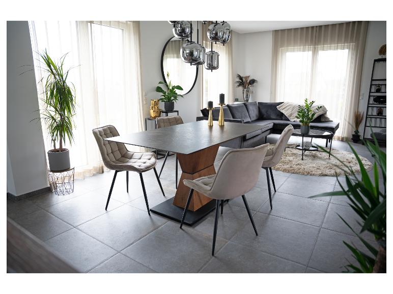 Modernes Esszimmer mit Holztisch und Polsterstühlen, grauem Sofa und Pflanzen.