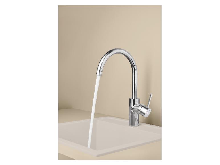 Verchromter Küchenhahn mit fließendem Wasser in einem beigen Spülbecken.