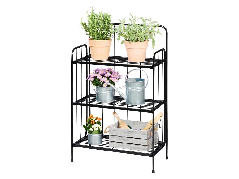 Schwarzes Metallregal mit drei Ebenen, Kräutern, Blumen und Gartengeräten.