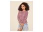 Frau in lila Lochstrick-Cardigan und Jeans-Shorts.