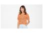 Frau in orangefarbenem Kurzarm-Strickpullover und hellen Jeansshorts.