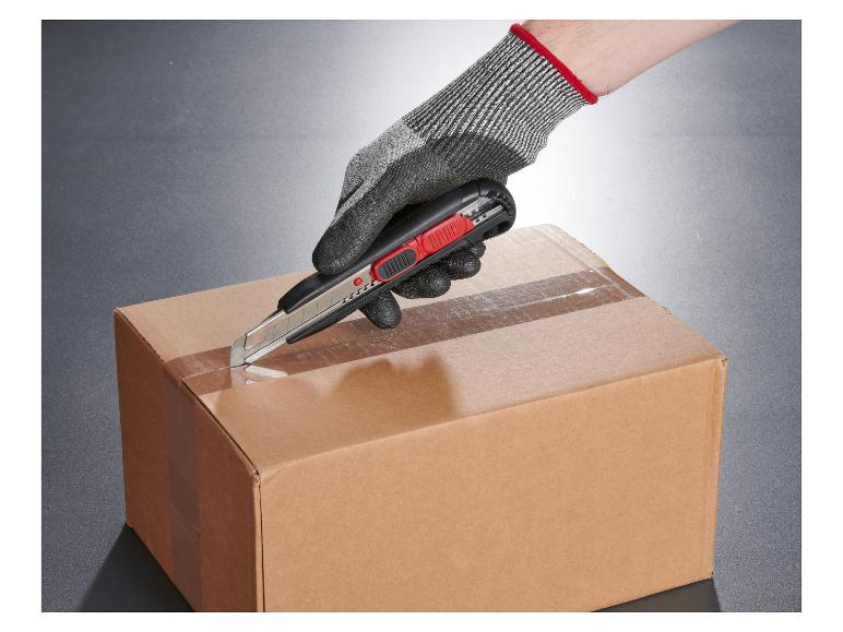 Eine behandschuhte Hand schneidet Klebeband von einem Karton mit einem Cuttermesser.