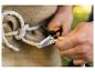 Hände schneiden Seil mit einem Messer, mit Sackleinen im Hintergrund.