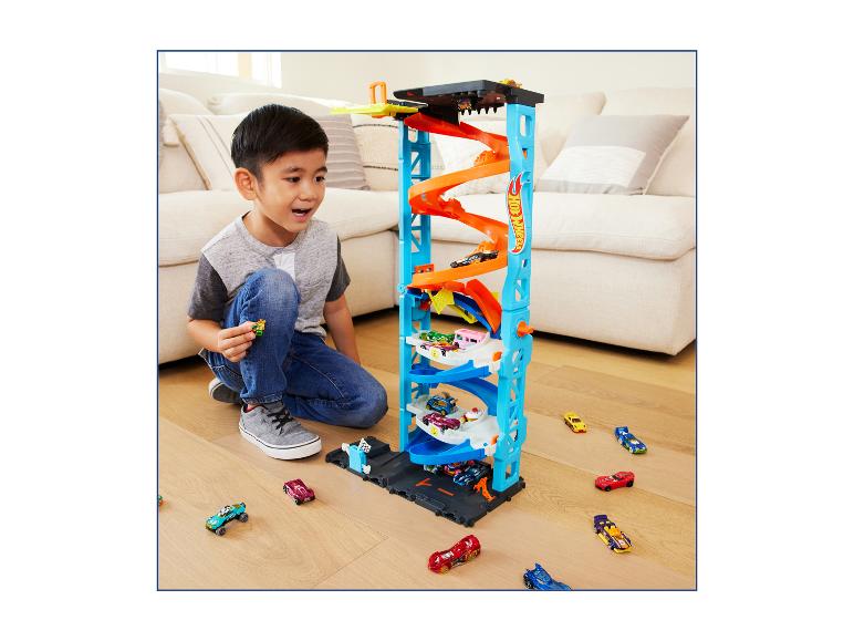 Junge spielt mit einem Hot Wheels Parkturm und Spielzeugautos.