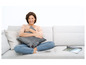 Eine Frau sitzt auf einem grauen Sofa mit einem Heizkissen.