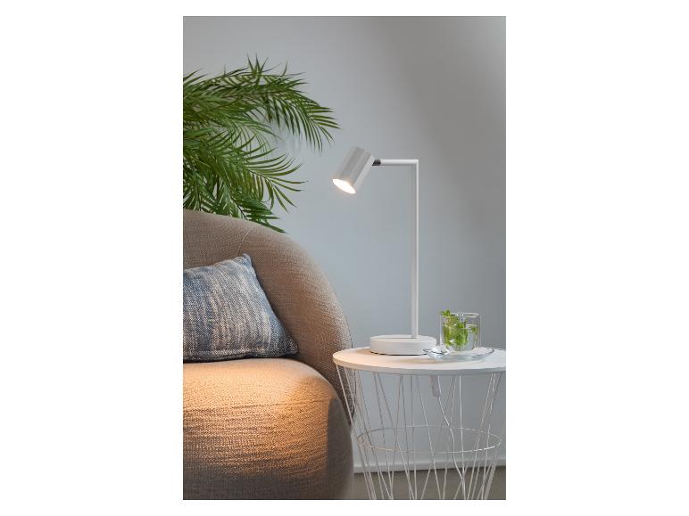 Moderne weiße Tischlampe neben einem bequemen Sessel.