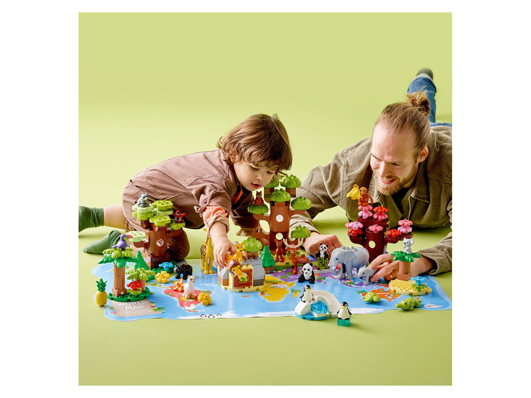 Zwei Kinder spielen mit LEGO DUPLO Steinen und Tieren auf einer Weltkarte.