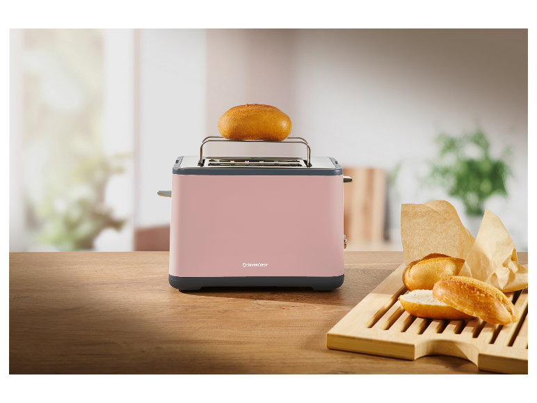 Ein rosa SilverCrest Toaster mit Brötchen auf einem Holzbrett.