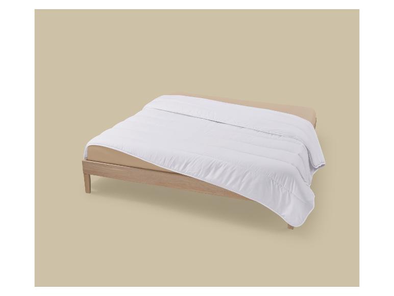 Weiße Bettdecke auf einem hellbraunen Holz-Bettgestell