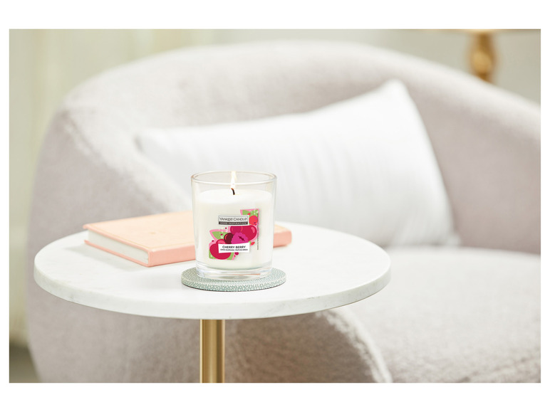 Eine Yankee Candle Cherry Berry Duftkerze auf einem Beistelltisch.