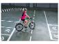 Frau mit Helm und Warnweste fährt E-Bike auf einem Parcours mit weißen Linien und Pfeilen.