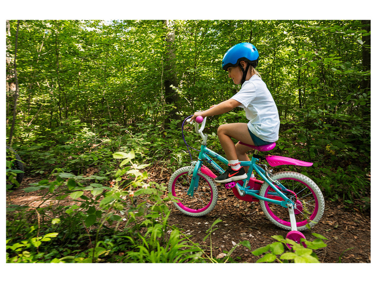 Ein Kind fährt im Wald auf einem Fahrrad mit Stützrädern.