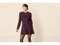 Frau in einem lila Strickkleid und schwarzer Strumpfhose.