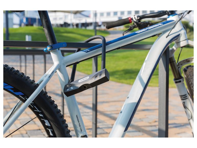 Mountainbike mit grauem Bügelschloss, an einem Fahrradständer befestigt