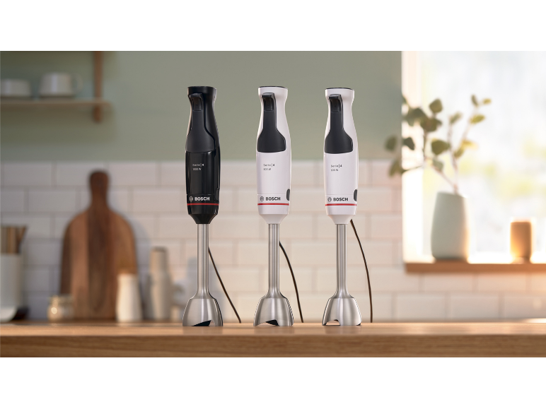 Drei Stabmixer mit unterschiedlicher Leistung auf einer hölzernen Küchenarbeitsplatte.
