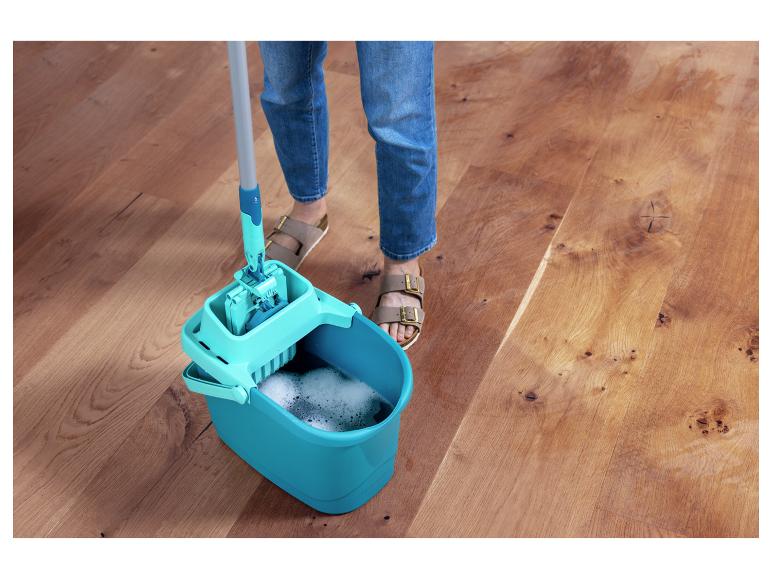 Person wischt einen Holzboden mit Eimer und Mopp.