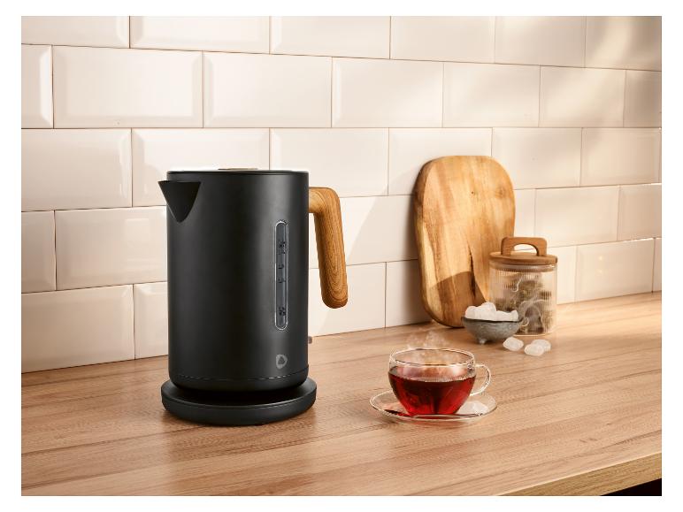 Schwarzer Wasserkocher mit Holzgriff auf einer Küchenarbeitsplatte mit einer Tasse Tee.