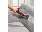 Mann reinigt ein graues Sofa mit einem rot-schwarzen Polsterreiniger.