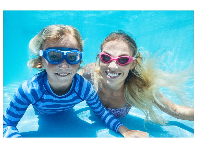 Zwei Personen in Schwimmbrillen und Badebekleidung unter Wasser, lächelnd in die Kamera.