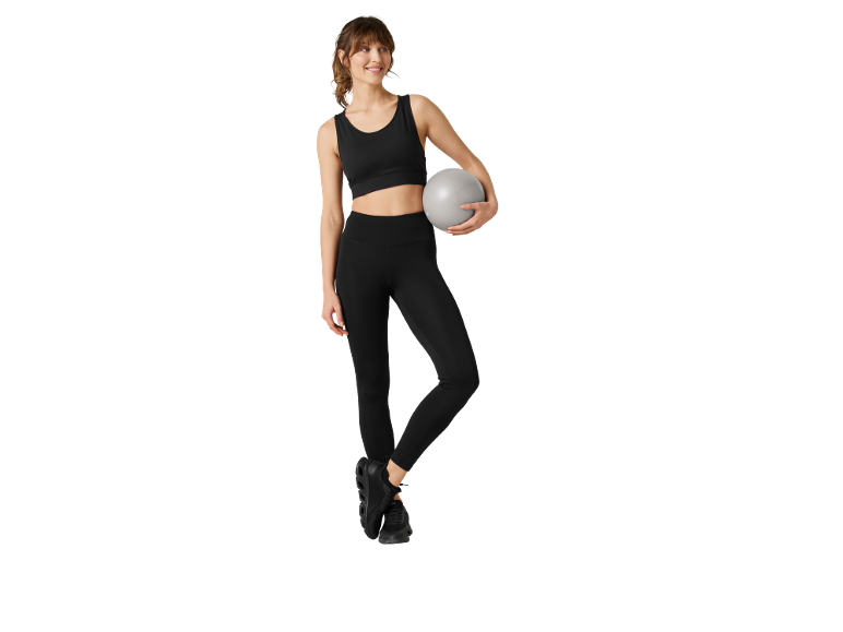 Frau in schwarzer Sportkleidung mit grauem Pilatesball.