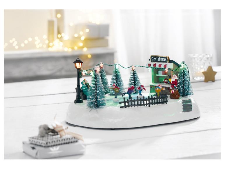Weihnachtsszene mit Eisbahn, Weihnachtsmann und festlichen Lichtern auf einem weißen Tisch.