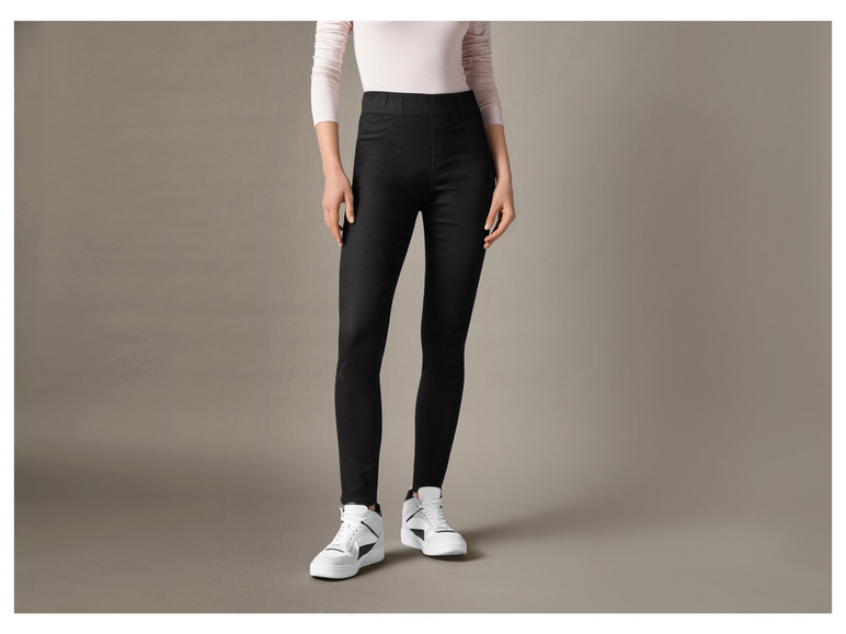 Eine Frau trägt schwarze Skinny Jeans und weiße Sneaker.