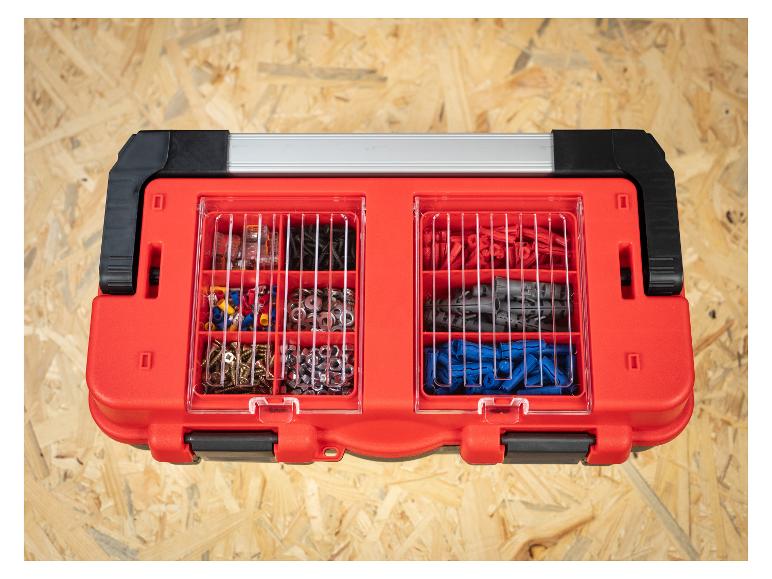 Rote Organizerbox mit verschiedenen Schrauben, Unterlegscheiben, Muttern und Dübeln auf Holzuntergrund.