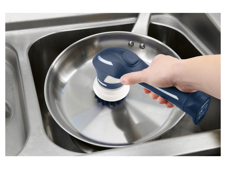 Ein blauer elektrischer Scheuerer wird zum Reinigen einer Pfanne in einem Spülbecken verwendet.