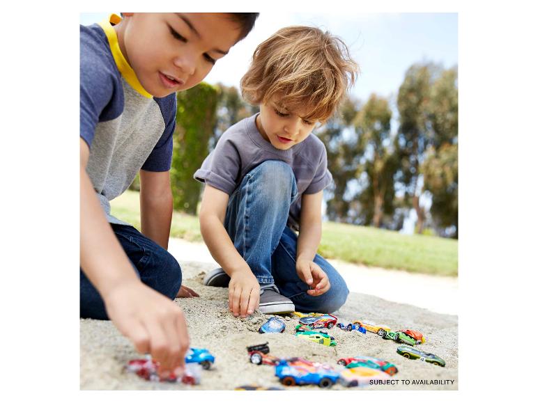 Zwei Jungen spielen draußen mit Spielzeugautos im Sand.
