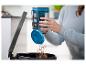 Person entleert einen Handstaubsauger mit blauem Filter in einen Mülleimer.