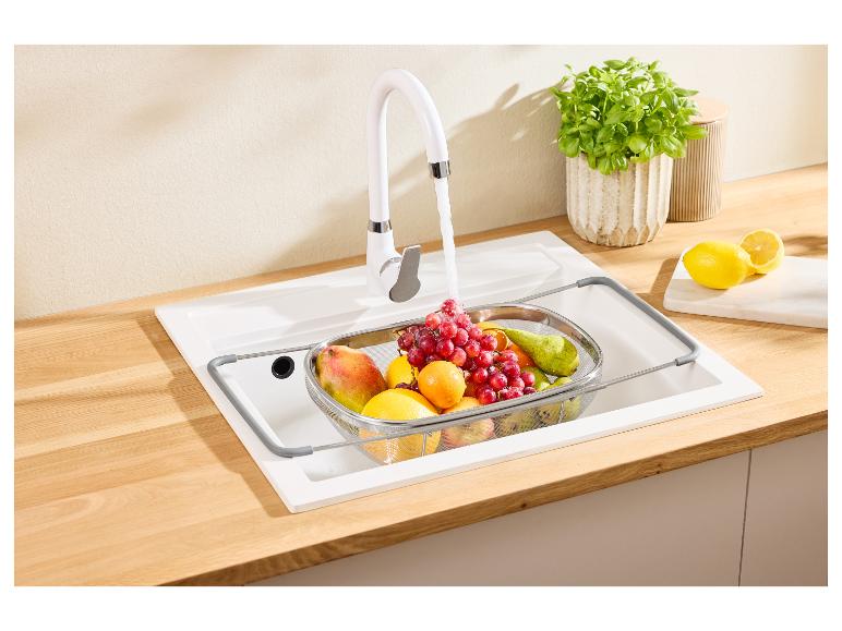 Weißer Küchenhahn mit Obst im Sieb in der Spüle und Zitronen auf der Arbeitsplatte.