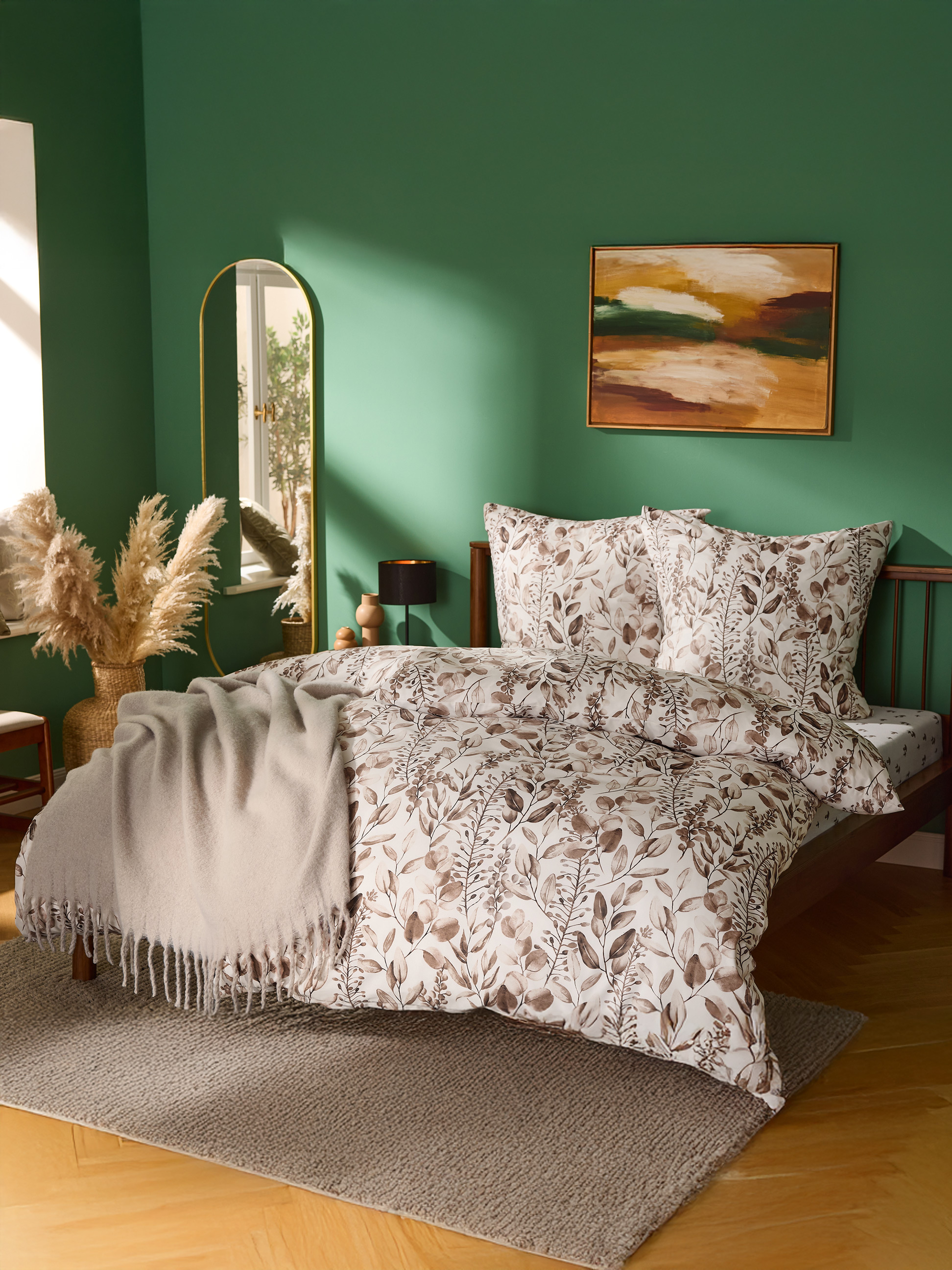Schlafzimmer mit grünen Wänden, Bett mit Blättermuster-Bettwäsche und beiger Decke.