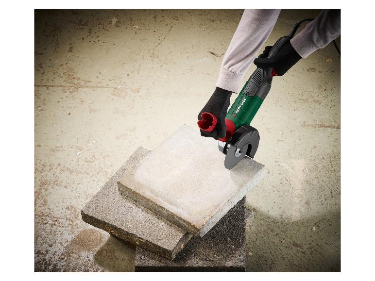 Eine Person mit Handschuhen verwendet eine Parkside Winkelschleifer zum Schneiden von Betonplatten.