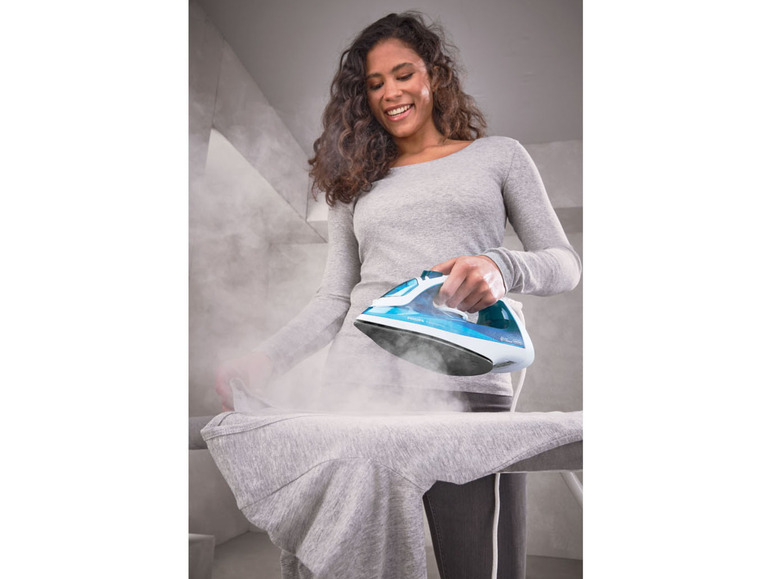 Eine Frau bügelt ein Hemd mit einem Philips Dampfbügeleisen.