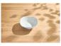Leere weiße Schale auf einem Holztisch mit Blattschatten.