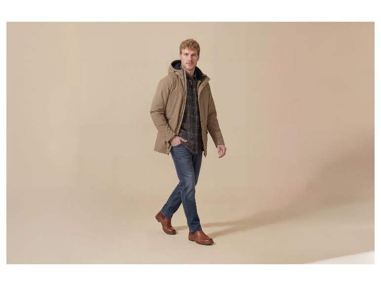 Mann in beiger Jacke, kariertem Hemd, Jeans und braunen Schuhen, gehend.