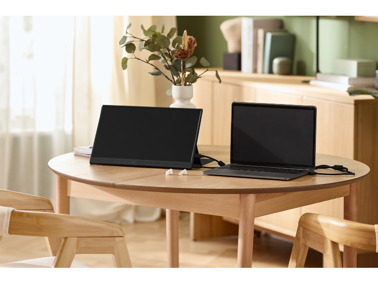 Ein tragbarer Monitor und ein Laptop, die auf einem Holztisch in einem hellen Raum angeschlossen sind.