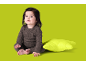 Baby in braunem Strampler sitzt neben einem grünen Kissen.