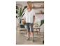 Frau in weißem T-Shirt und grauen Leggings mit Handtasche steht in gemütlichem Raum.