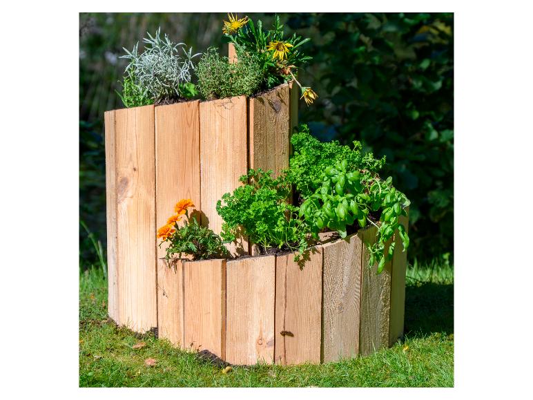 Hölzernes Spiralbeet mit Kräutern und Blumen auf Rasen.