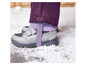 Graue Kinderschuhe mit lila Hosenbeinen im Schnee.